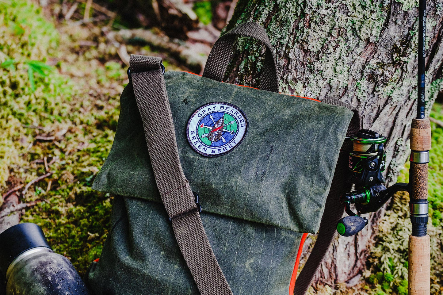 GB2 Waxed Canvas Haversack with Adjustable Strap with water bottle and fishing pole angled