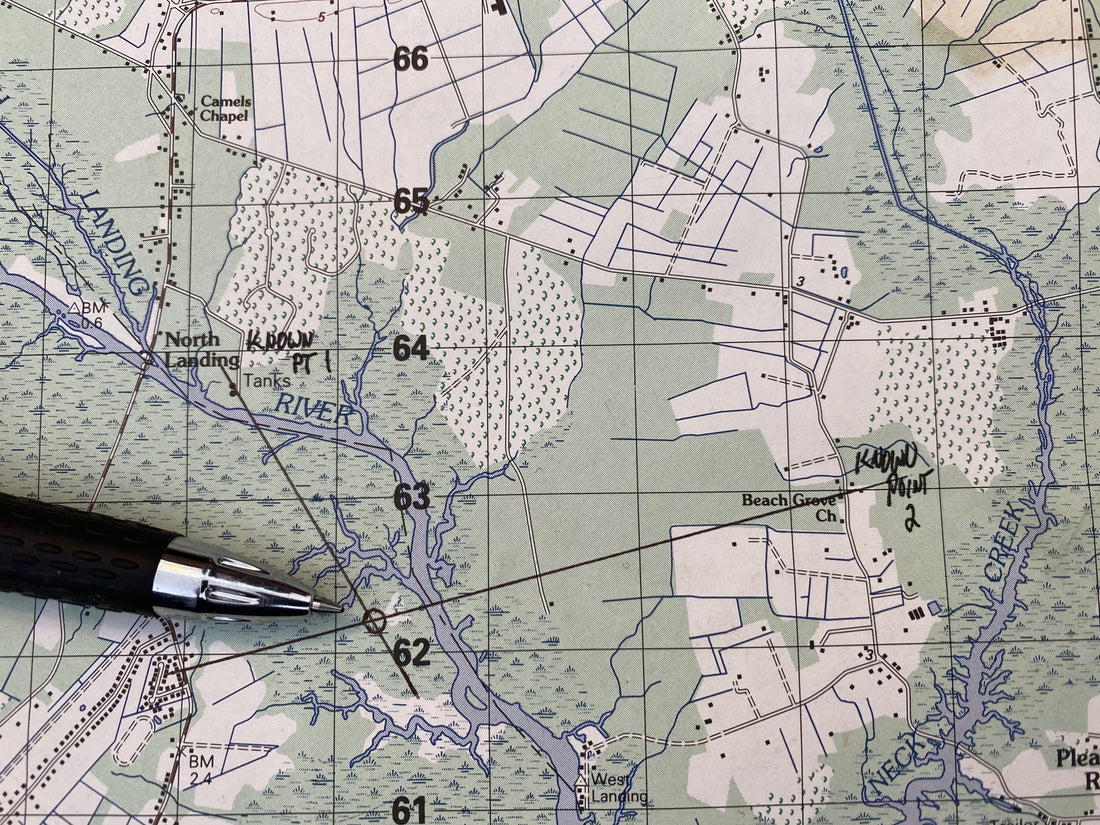 Topographic map with a resection plotted — reverse azimuths from two known features crossing to fix an unknown position