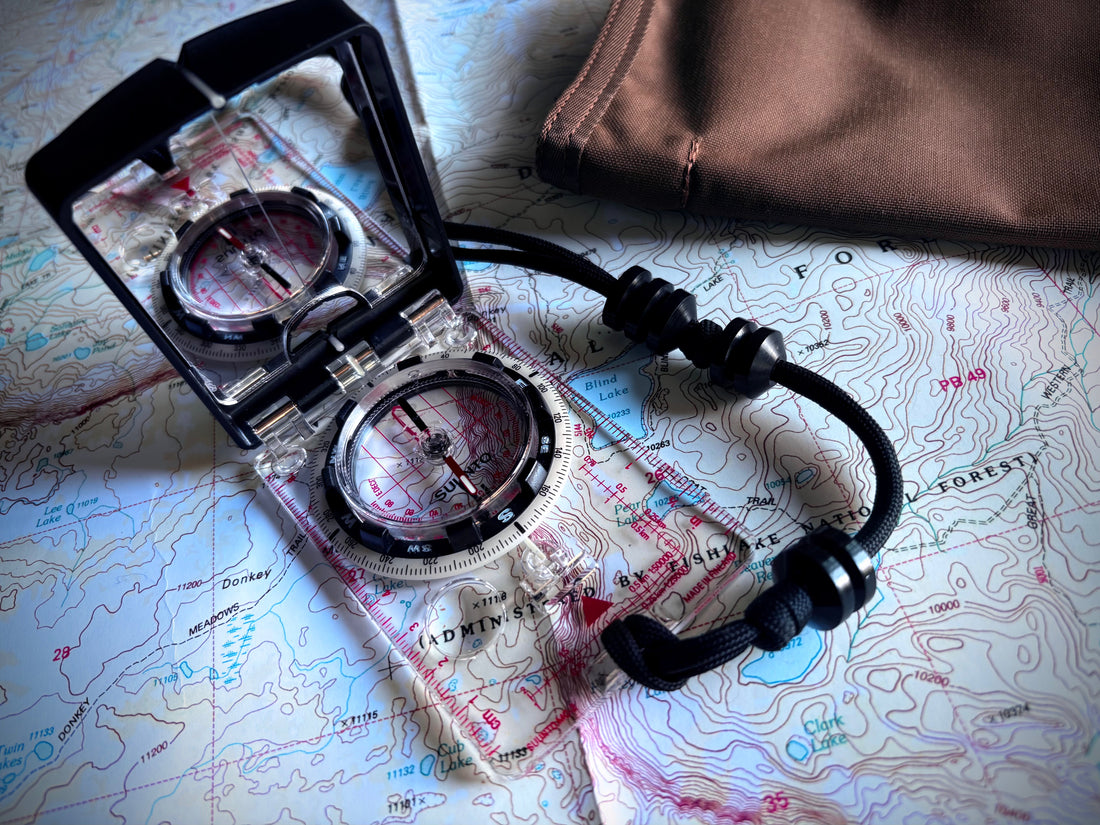 Suunto MC-2 mirror compass resting on a topographic map, bezel indexed to a magnetic azimuth