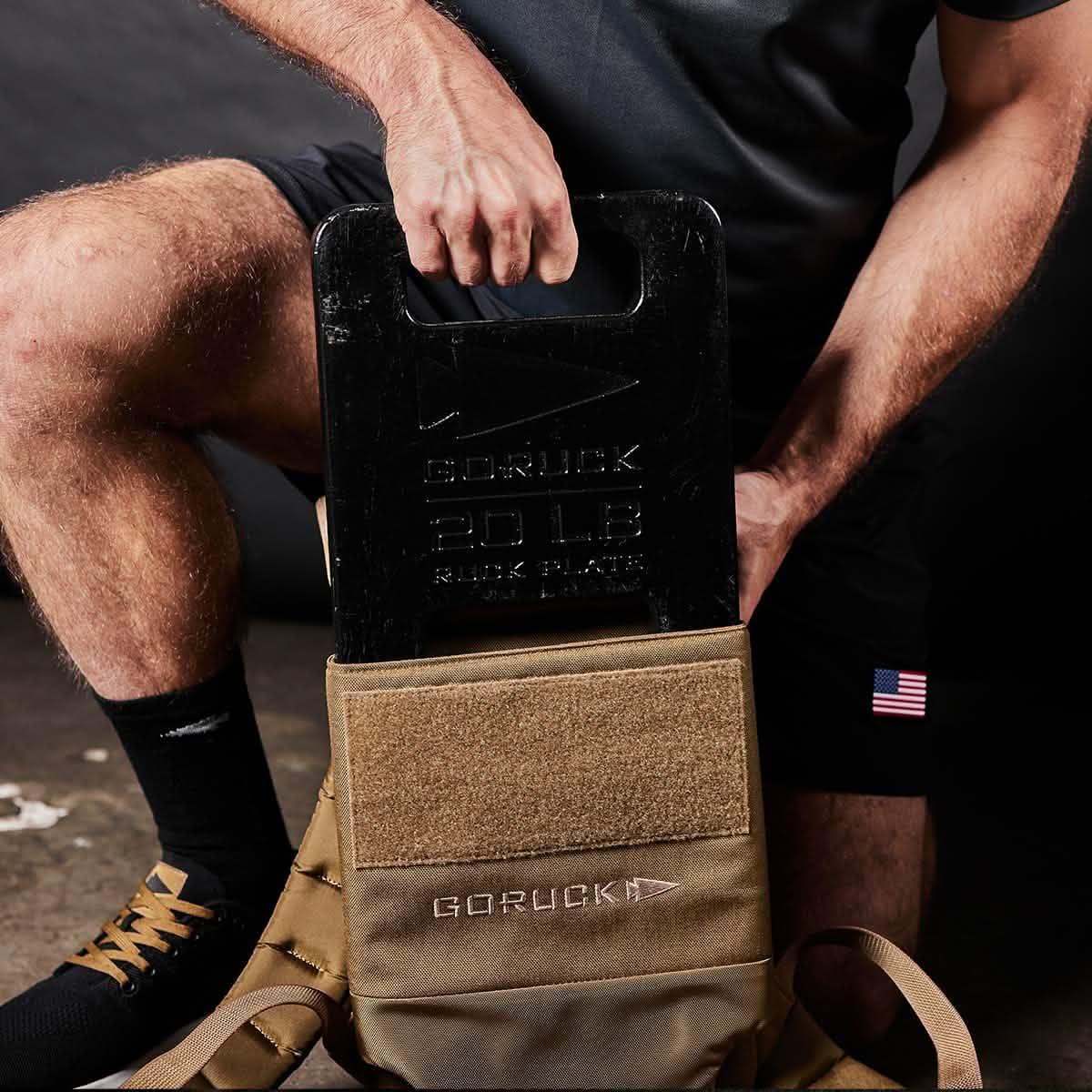 Man pulling GoRuck ruck plates out of a tan ruck carrier