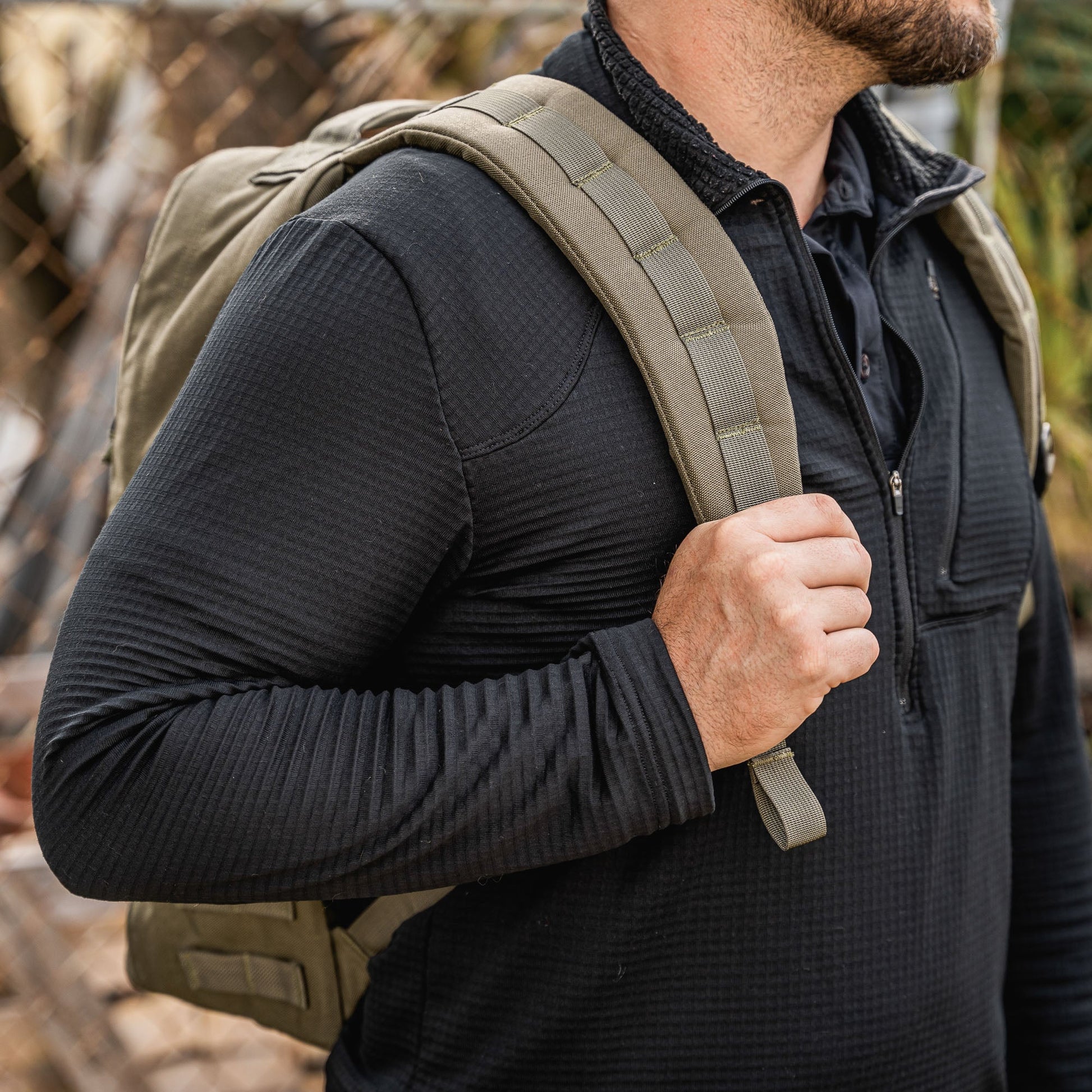 Man in a woodland environment carrying a ranger green GoRuck rucksack