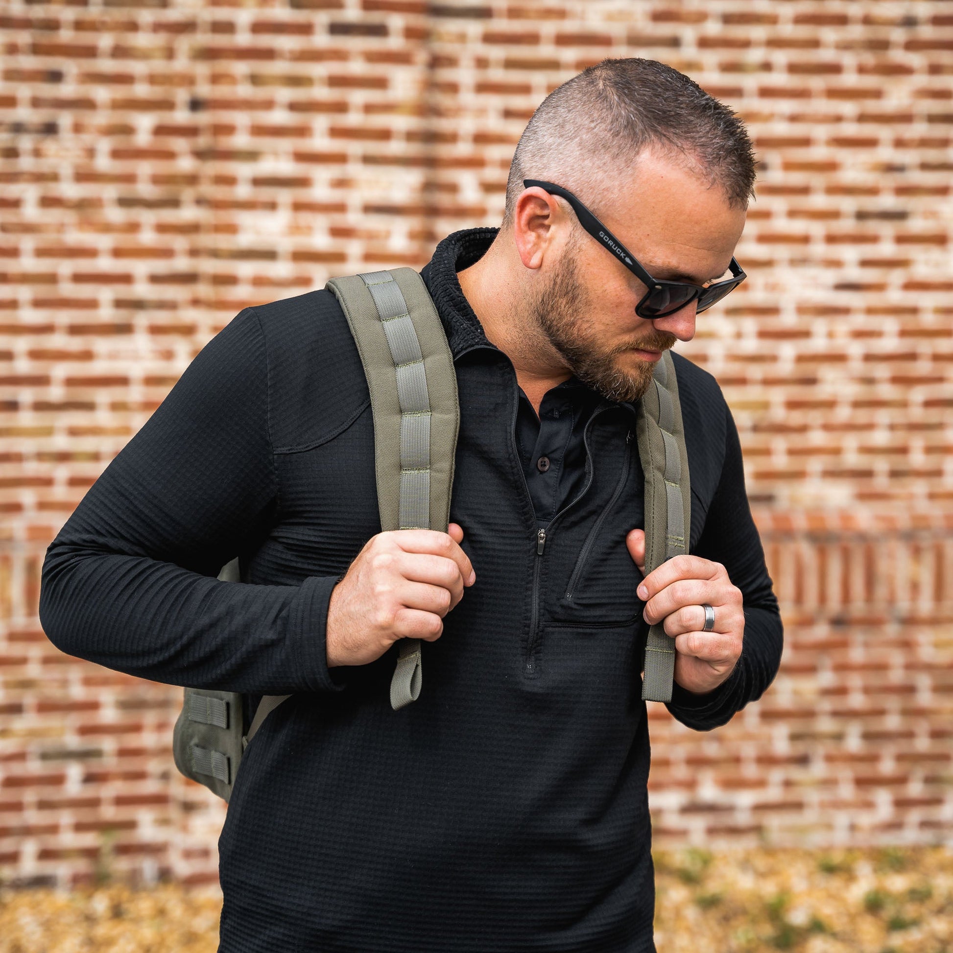 Man in an urban environment carrying a ranger green GoRuck rucksack