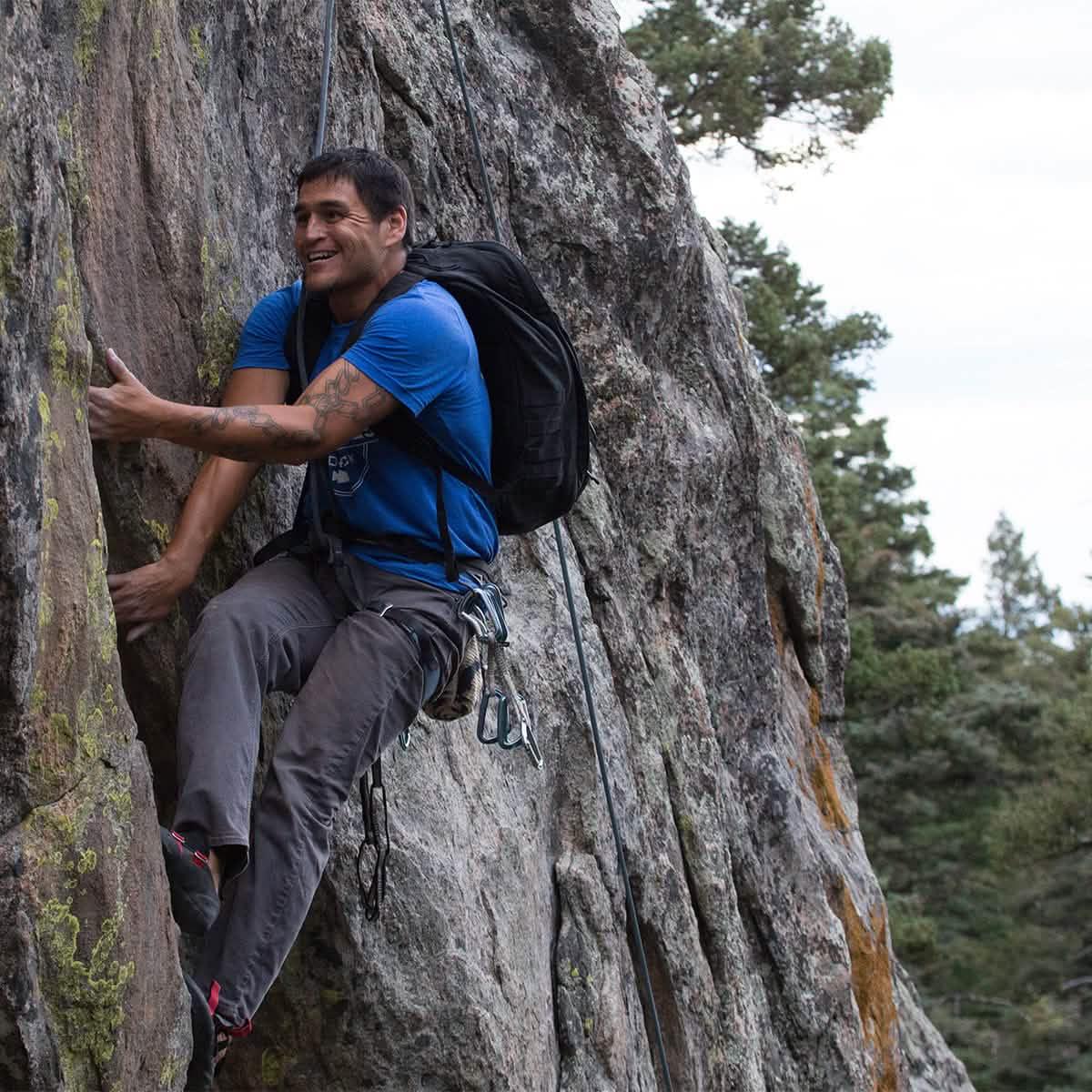 Man rock climbing wearing a black GoRuck rucksack