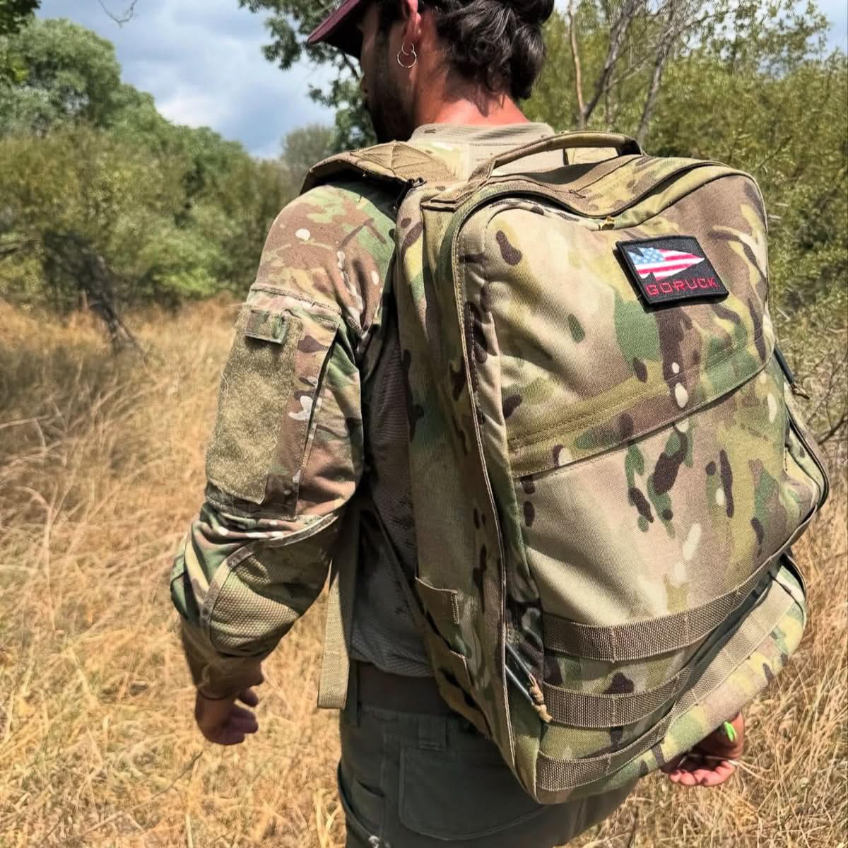 Man wearing camouflage in the field wearing a camo GoRuck rucksack