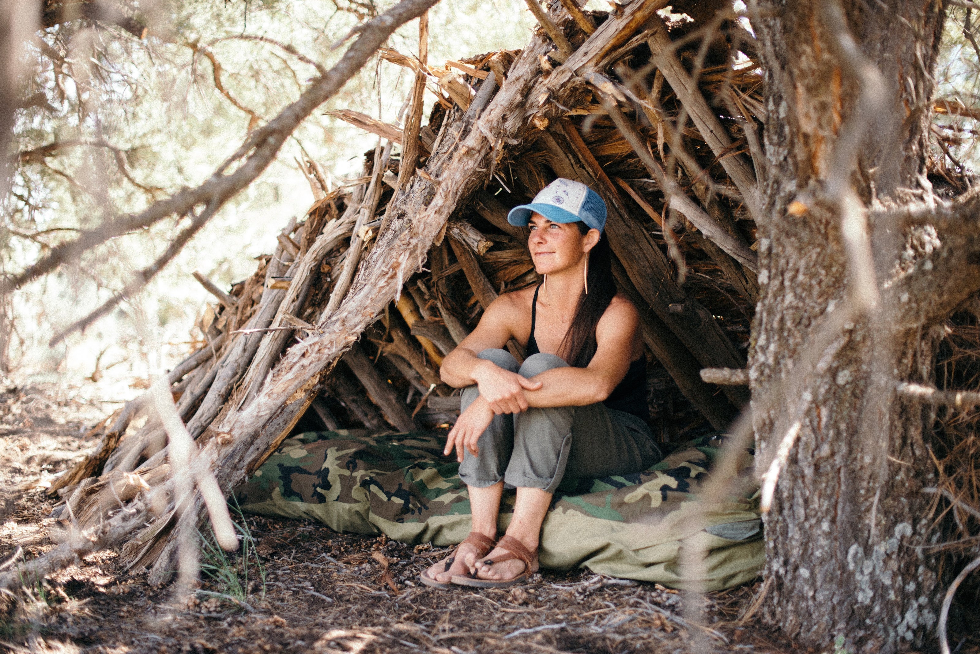 Kirsten sitting in front of a primitive shelter