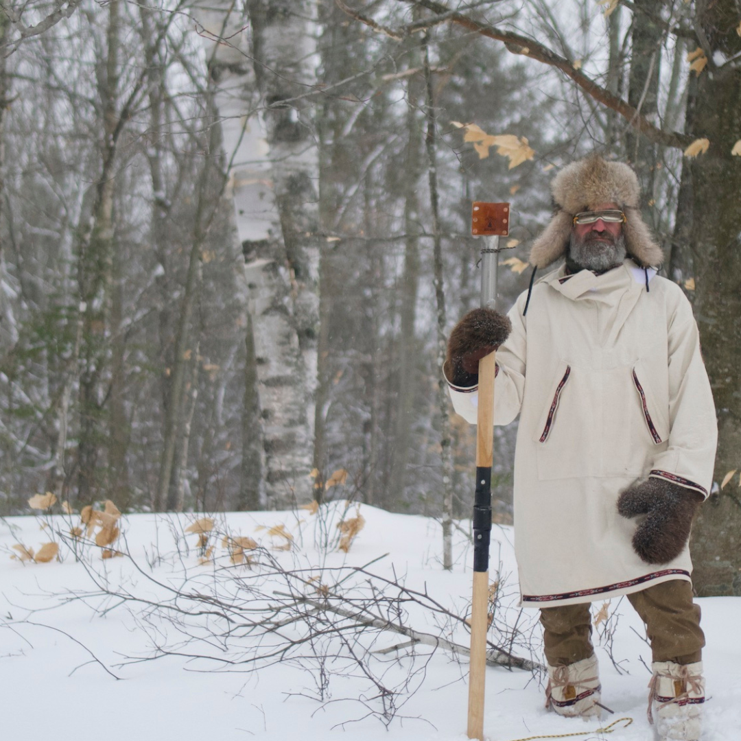 Person in winter clothing with a snowshoe in a snowy forest