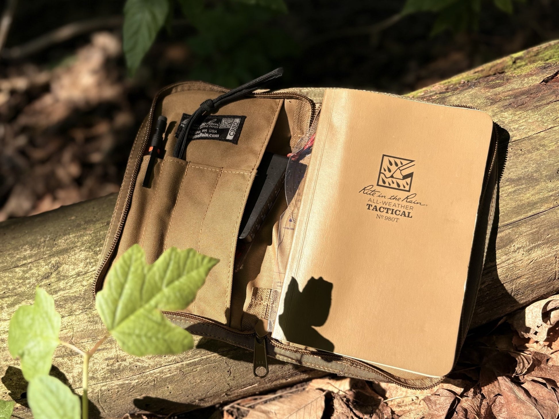 Tactical pouch and notebook on a wooden surface with natural background