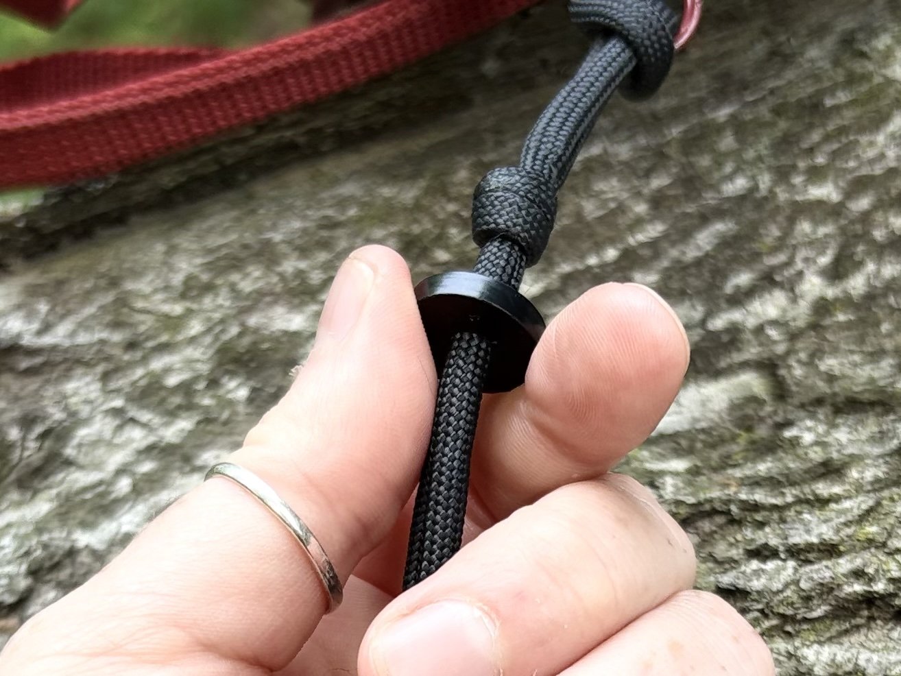 Close-up of a hand holding a GB2 Ranger Pace Counter: Accurate Manual Distance Tracking Tool for Land Navigation on log with wasp