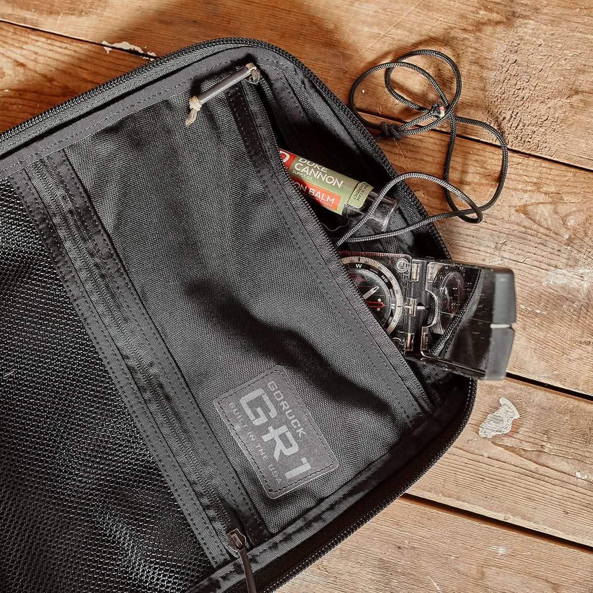 Black GoRuck rucksack with a compass and other small items inside an interior pocket