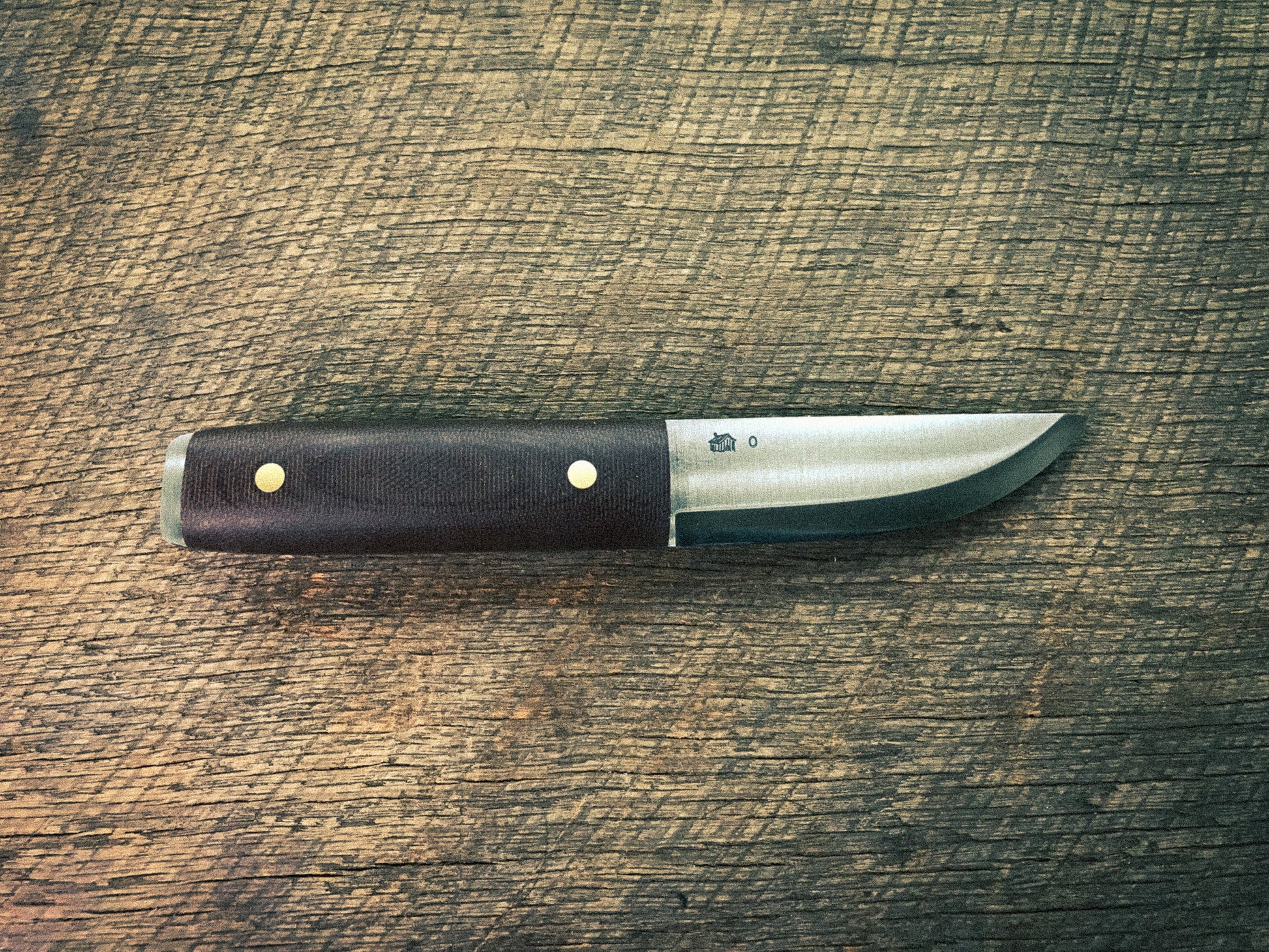 Knife with a brown micarta handle on a wooden surface