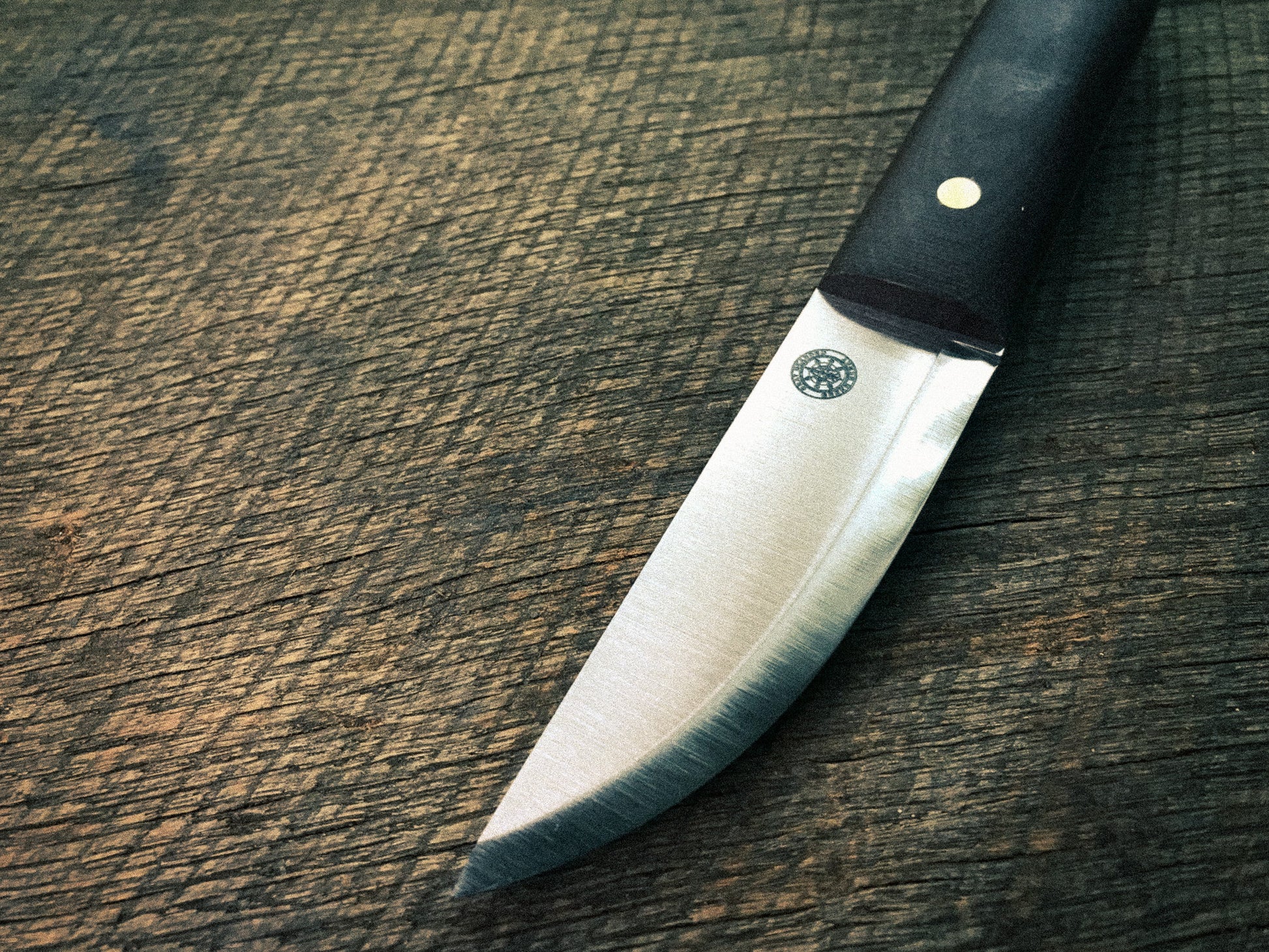 Knife with a brown micarta handle on a wooden surface