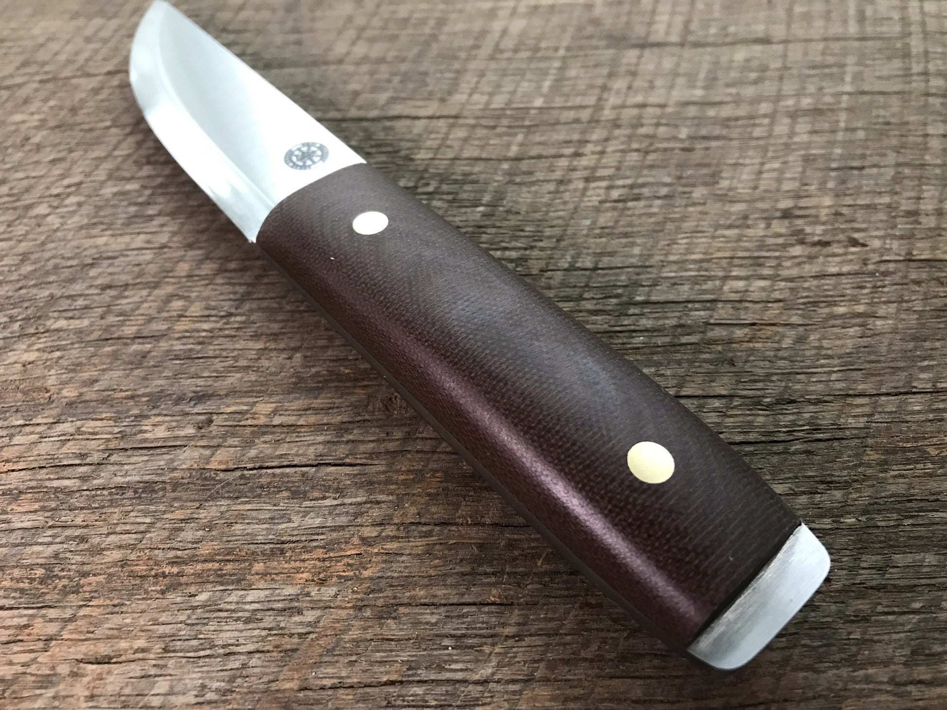 Knife with a brown handle and silver blade on a wooden surface