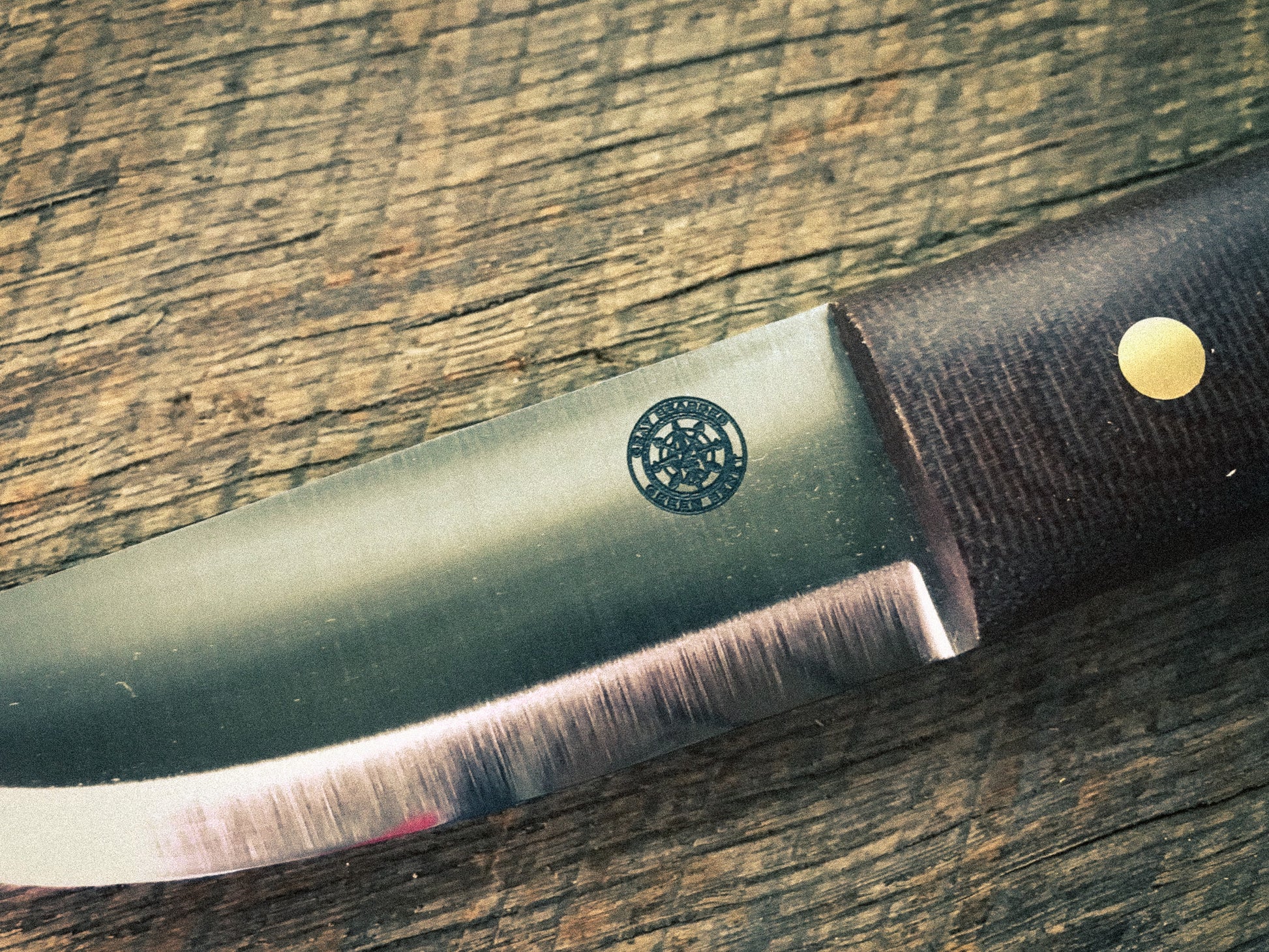 Knife with a brown handle and visible brand logo on a wooden surface