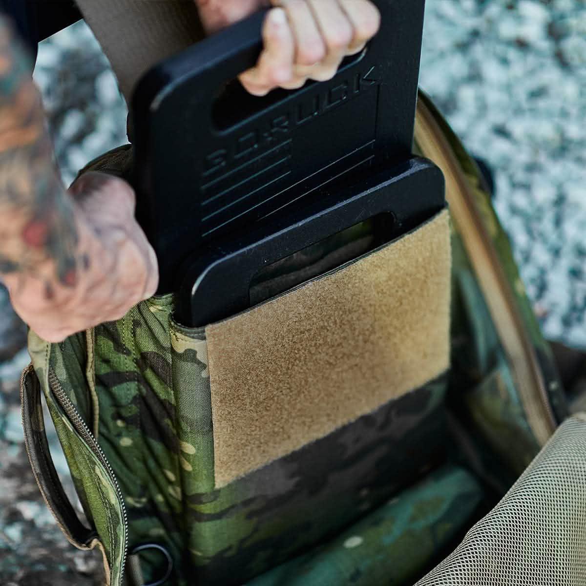 Man pulling GoRuck ruck plates out of a camo rucksack