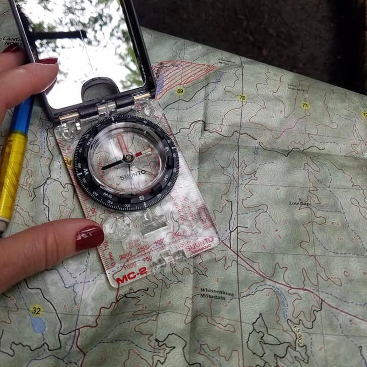 Master Navigator Course - Map Reading and Land Navigation Course Suunto MC2 Compass and Top Map with Woman's hand